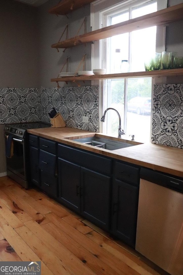 kitchen with stainless steel appliances, plenty of natural light, sink, and light hardwood / wood-style floors