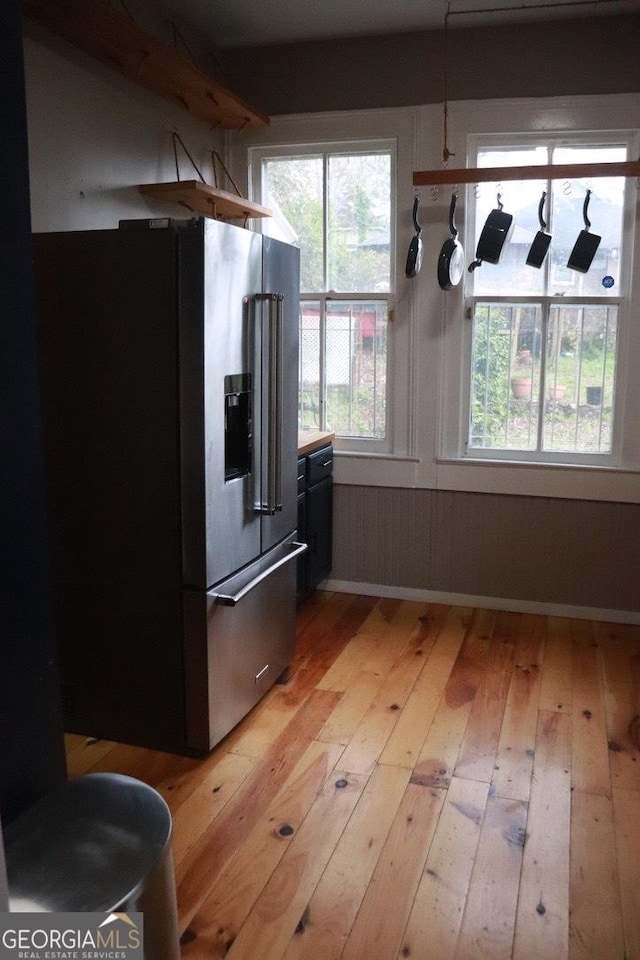 kitchen featuring high end refrigerator, wood walls, and light wood-type flooring