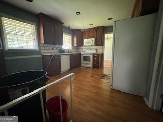 kitchen with backsplash, white appliances, and wood-type flooring