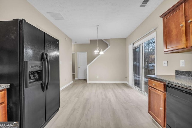 kitchen with hanging light fixtures, black appliances, a textured ceiling, and light wood-type flooring