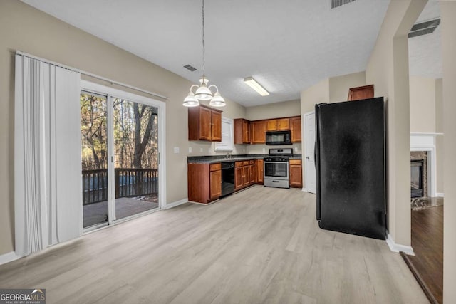 kitchen with light wood-type flooring, a notable chandelier, pendant lighting, a premium fireplace, and black appliances