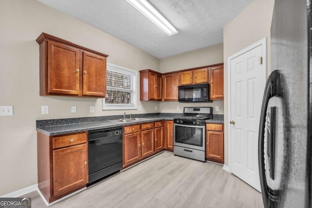 kitchen featuring sink, black appliances, a textured ceiling, and light wood-type flooring