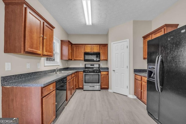 kitchen featuring sink, light hardwood / wood-style flooring, a textured ceiling, and black appliances