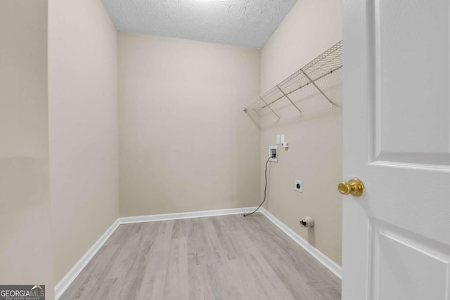 washroom with hookup for a washing machine, hookup for an electric dryer, a textured ceiling, and light hardwood / wood-style floors