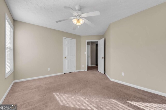 unfurnished bedroom featuring ceiling fan, light colored carpet, and a textured ceiling