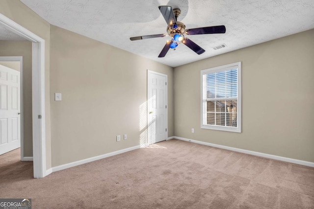 unfurnished bedroom with light carpet, a textured ceiling, and ceiling fan