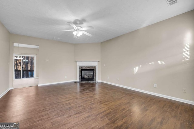 unfurnished living room with dark hardwood / wood-style flooring, a textured ceiling, a high end fireplace, and ceiling fan