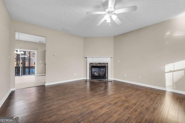 unfurnished living room featuring dark wood-type flooring, ceiling fan, a high end fireplace, and a textured ceiling