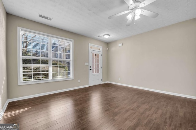 empty room featuring dark hardwood / wood-style flooring, ceiling fan, and a textured ceiling