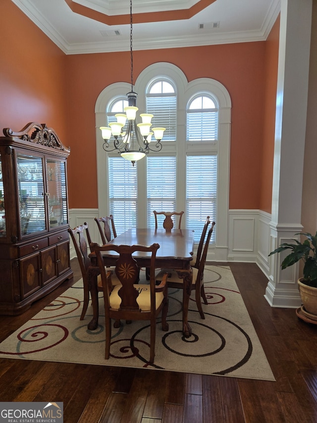 dining area featuring ornamental molding, dark wood-type flooring, a chandelier, and a tray ceiling