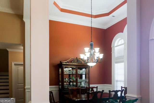 dining space featuring ornamental molding, a tray ceiling, a chandelier, and a high ceiling