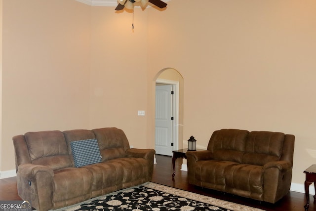 living room with dark hardwood / wood-style flooring, ornamental molding, and ceiling fan