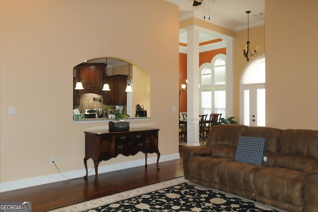 living room featuring a notable chandelier, hardwood / wood-style flooring, ornamental molding, and a towering ceiling