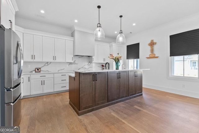 kitchen featuring tasteful backsplash, an island with sink, stainless steel fridge with ice dispenser, and white cabinets