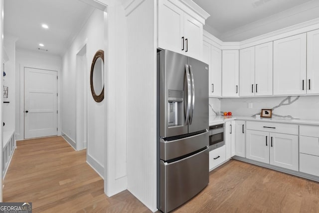 kitchen featuring stainless steel refrigerator with ice dispenser, backsplash, oven, and white cabinets