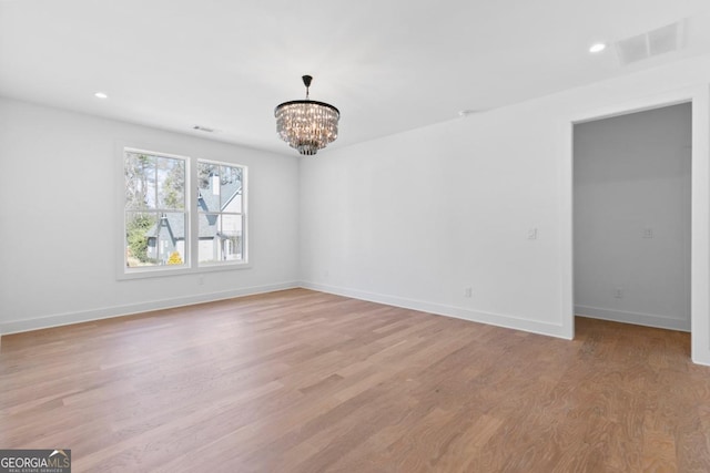 unfurnished room featuring light hardwood / wood-style flooring and a notable chandelier