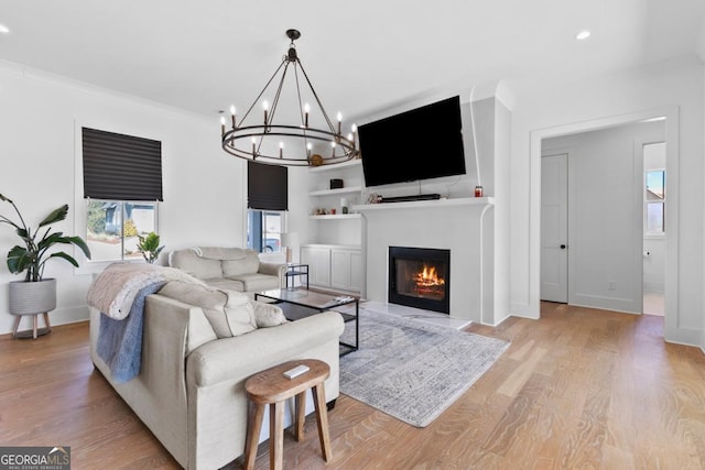 living room with built in shelves, light hardwood / wood-style flooring, and ornamental molding