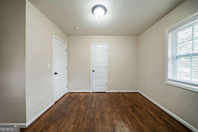 spare room featuring dark hardwood / wood-style flooring and a healthy amount of sunlight