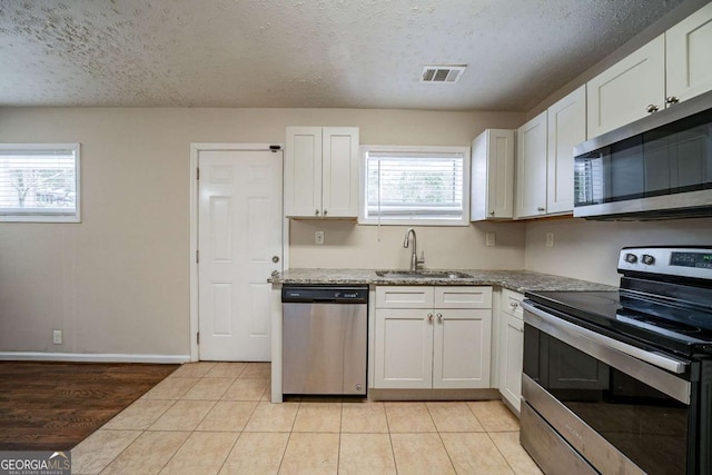 kitchen with stainless steel appliances, sink, a textured ceiling, and white cabinets