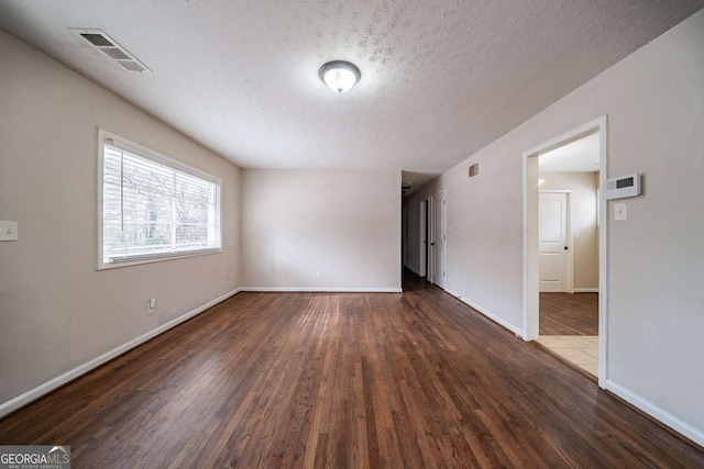 spare room with dark wood-type flooring and a textured ceiling