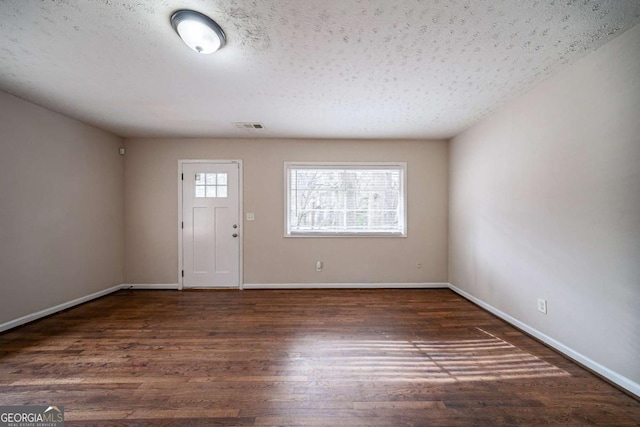 foyer entrance with a textured ceiling and dark hardwood / wood-style flooring