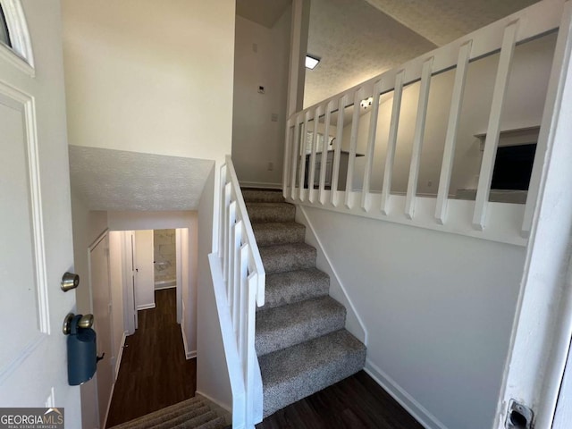 stairs featuring wood-type flooring and a textured ceiling