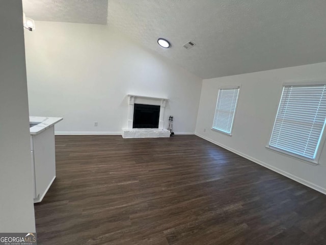 unfurnished living room with vaulted ceiling, dark wood-type flooring, and a textured ceiling