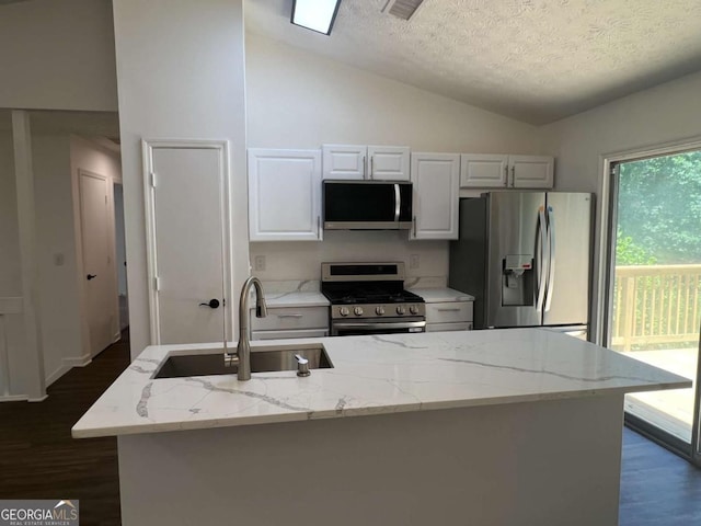 kitchen featuring lofted ceiling, sink, stainless steel appliances, light stone countertops, and a textured ceiling