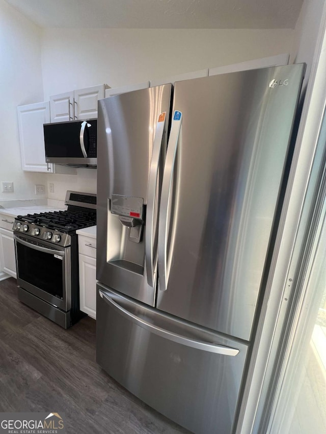 kitchen with dark wood-type flooring, stainless steel appliances, vaulted ceiling, and white cabinets