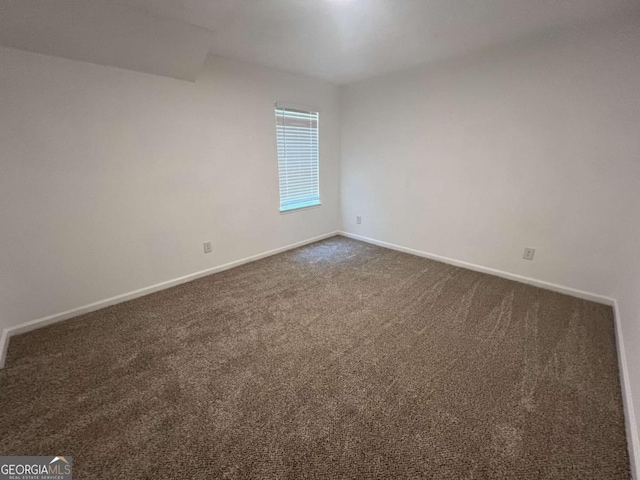 spare room with dark colored carpet