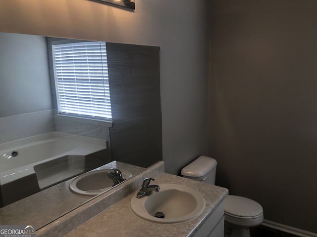 bathroom with vanity, a tub, and toilet