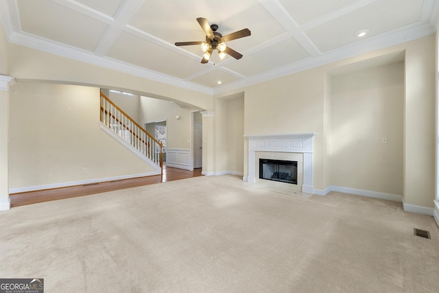 unfurnished living room with ceiling fan, coffered ceiling, light carpet, and beam ceiling