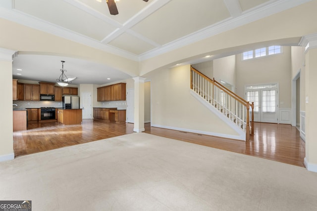 unfurnished living room with decorative columns, carpet flooring, coffered ceiling, ceiling fan, and crown molding