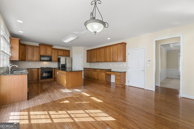 kitchen with stove, hanging light fixtures, a center island, wood-type flooring, and stainless steel fridge with ice dispenser