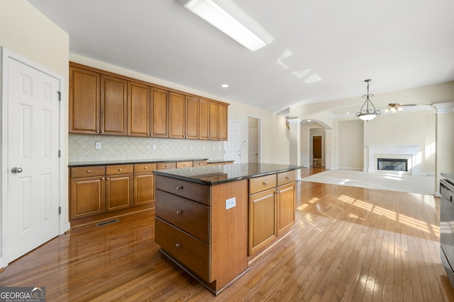 kitchen featuring a center island, pendant lighting, dark stone counters, hardwood / wood-style floors, and decorative backsplash