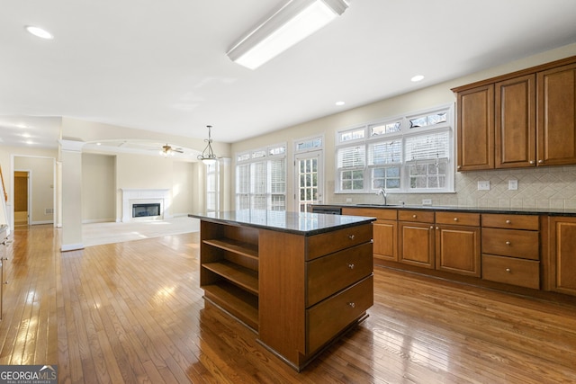 kitchen with wood-type flooring, a kitchen island, backsplash, and decorative light fixtures