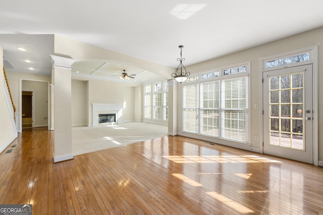 unfurnished living room with light hardwood / wood-style flooring, ceiling fan, and ornate columns