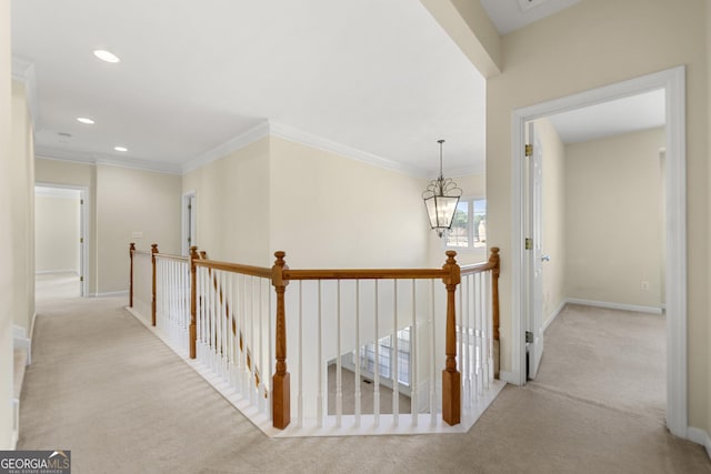 hallway with crown molding, light colored carpet, and an inviting chandelier