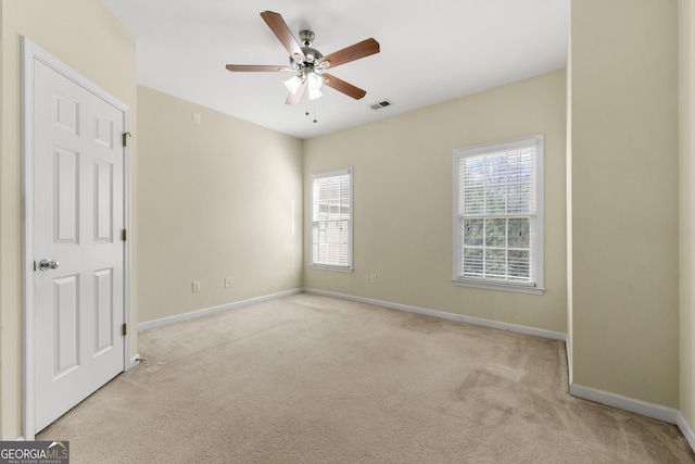 empty room with light carpet, a wealth of natural light, and ceiling fan