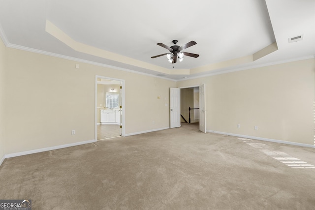 unfurnished bedroom with crown molding, a tray ceiling, ensuite bath, and ceiling fan