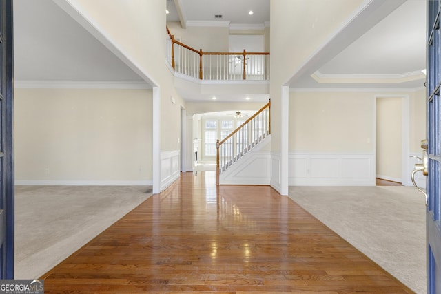 carpeted entrance foyer featuring crown molding and a towering ceiling