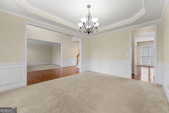 spare room featuring a tray ceiling, crown molding, and an inviting chandelier