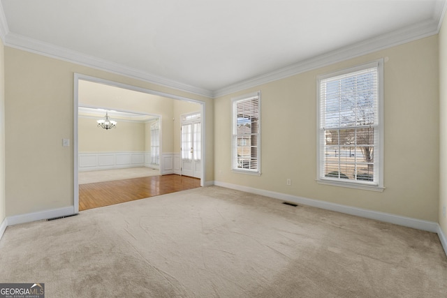 spare room featuring light carpet, crown molding, and an inviting chandelier