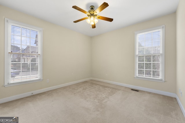 carpeted empty room with ceiling fan and plenty of natural light