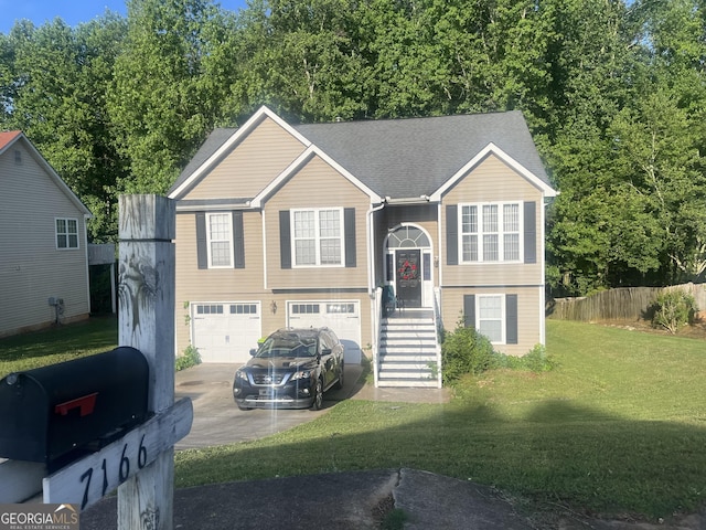 bi-level home with an attached garage, fence, driveway, roof with shingles, and a front lawn