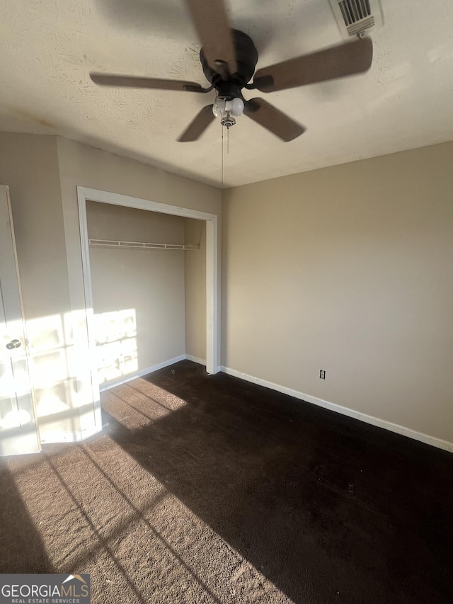 unfurnished bedroom with a textured ceiling, a ceiling fan, visible vents, baseboards, and carpet