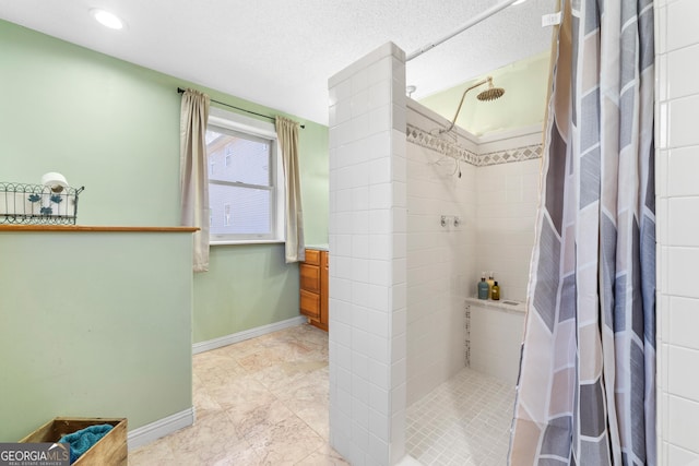 bathroom featuring tiled shower and baseboards