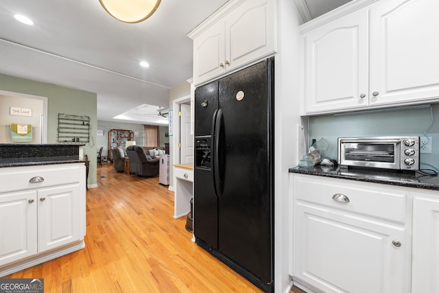 kitchen with light wood finished floors, black fridge with ice dispenser, white cabinetry, and a toaster