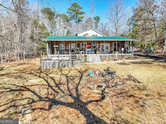 back of house featuring a porch, metal roof, and a lawn