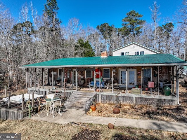 rear view of property featuring covered porch and metal roof